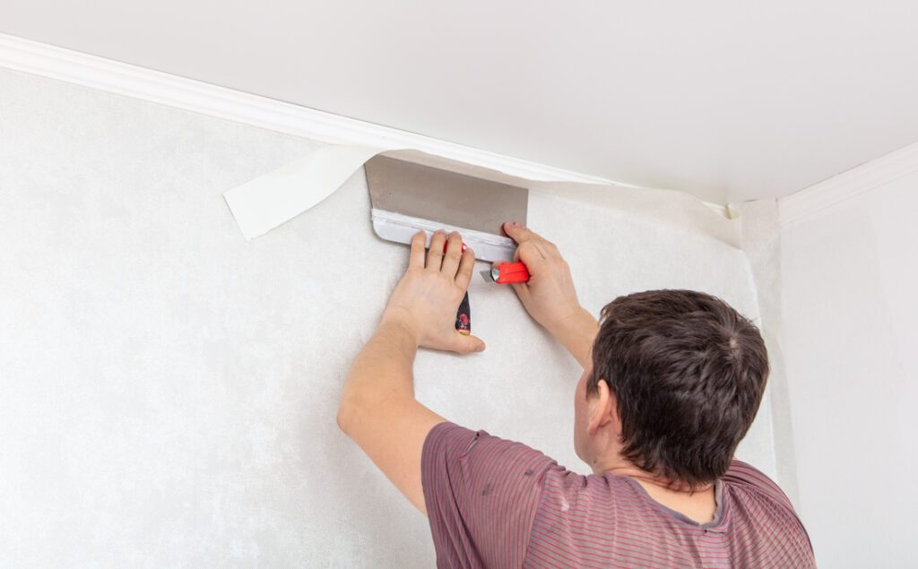 Decorator pastes wallpaper on the walls in a room