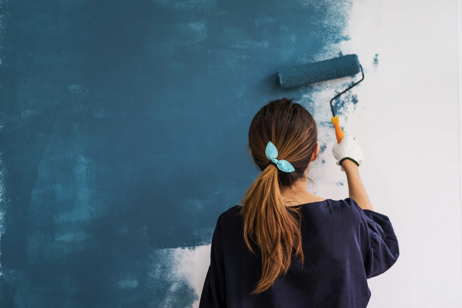 woman painting wall blue